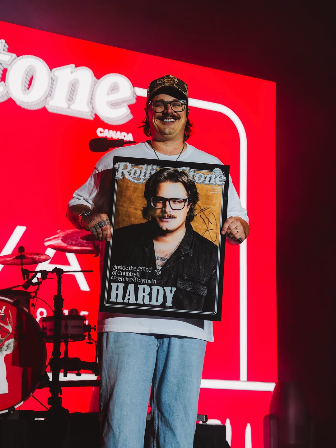 HARDY smiling on stage holding his Rolling Stone Canada cover portrait