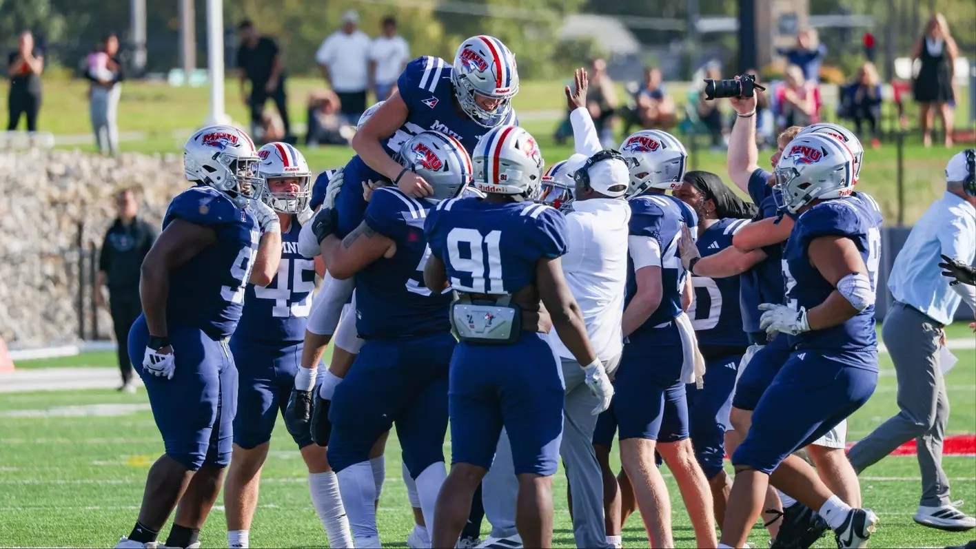 MidAmerica Nazarene football players celebrate on the field, lifting a teammate, ahead of their Week 9 game at Baker
