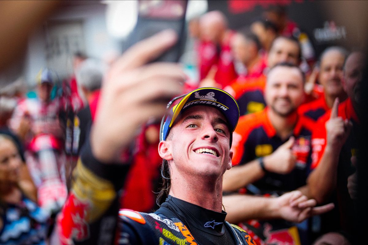 Pedro Acosta in Red Bull KTM leathers smiling and holding up a phone in front of his team after the Sprint at Sepang for the PETRONAS Grand Prix of Malaysia
