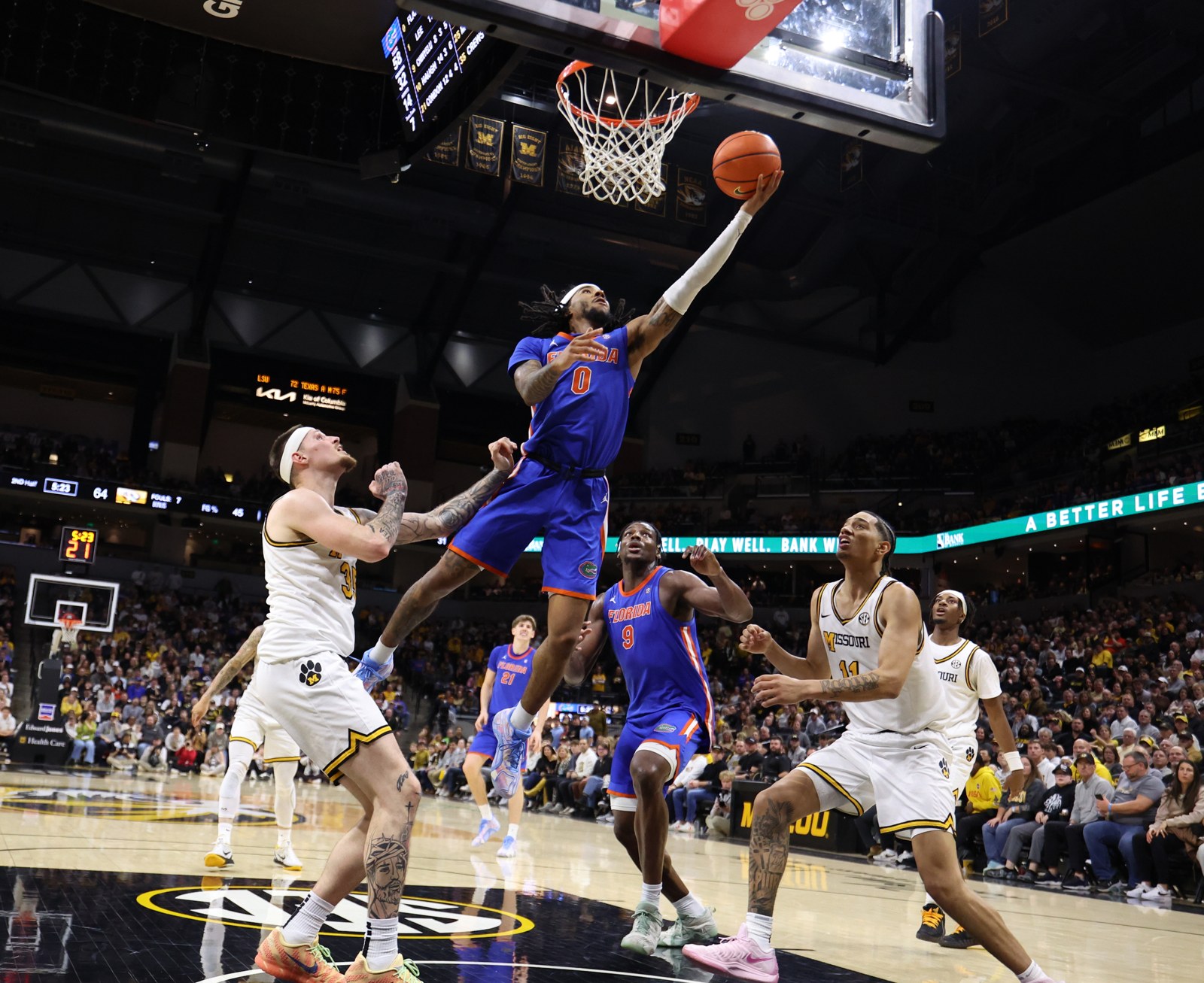 Florida Gators guard Boogie Fland lays the ball up against Missouri defenders during a game.