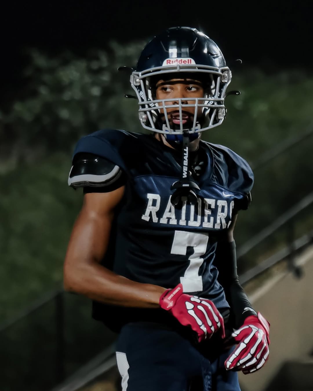A Redan Raiders player in a navy jersey with No. 2 and a navy helmet on the field at night under the stadium lights
