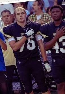 Two Plant Panthers players in black uniforms standing on the field with hands over their hearts before a game