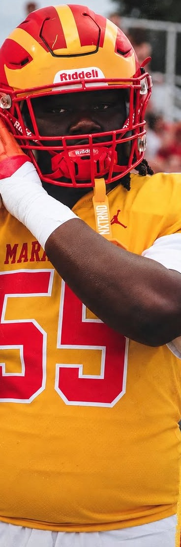 Clearwater Central Catholic Marauders player in a gold jersey and red-and-gold helmet adjusting his helmet on the sideline