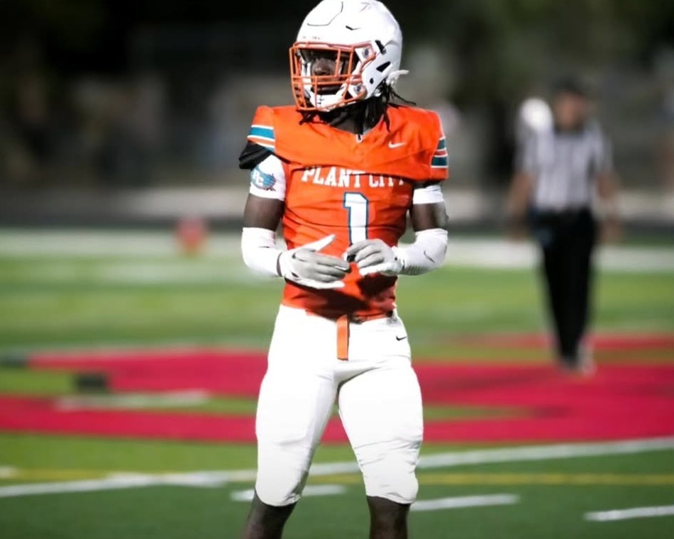 Plant City Raiders player Masiyah Limehouse in an orange jersey and white helmet standing on the field during a night game