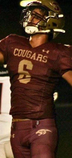 Countryside Cougars player in a maroon uniform and gold helmet celebrating on the field at night