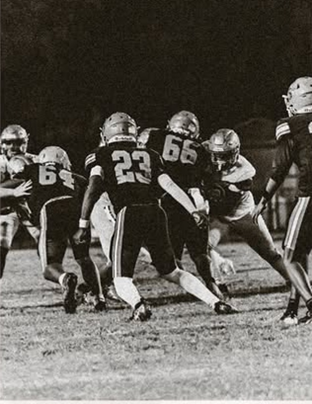 Black and white game photo of Bartow Yellow Jackets offensive linemen blocking during a night game