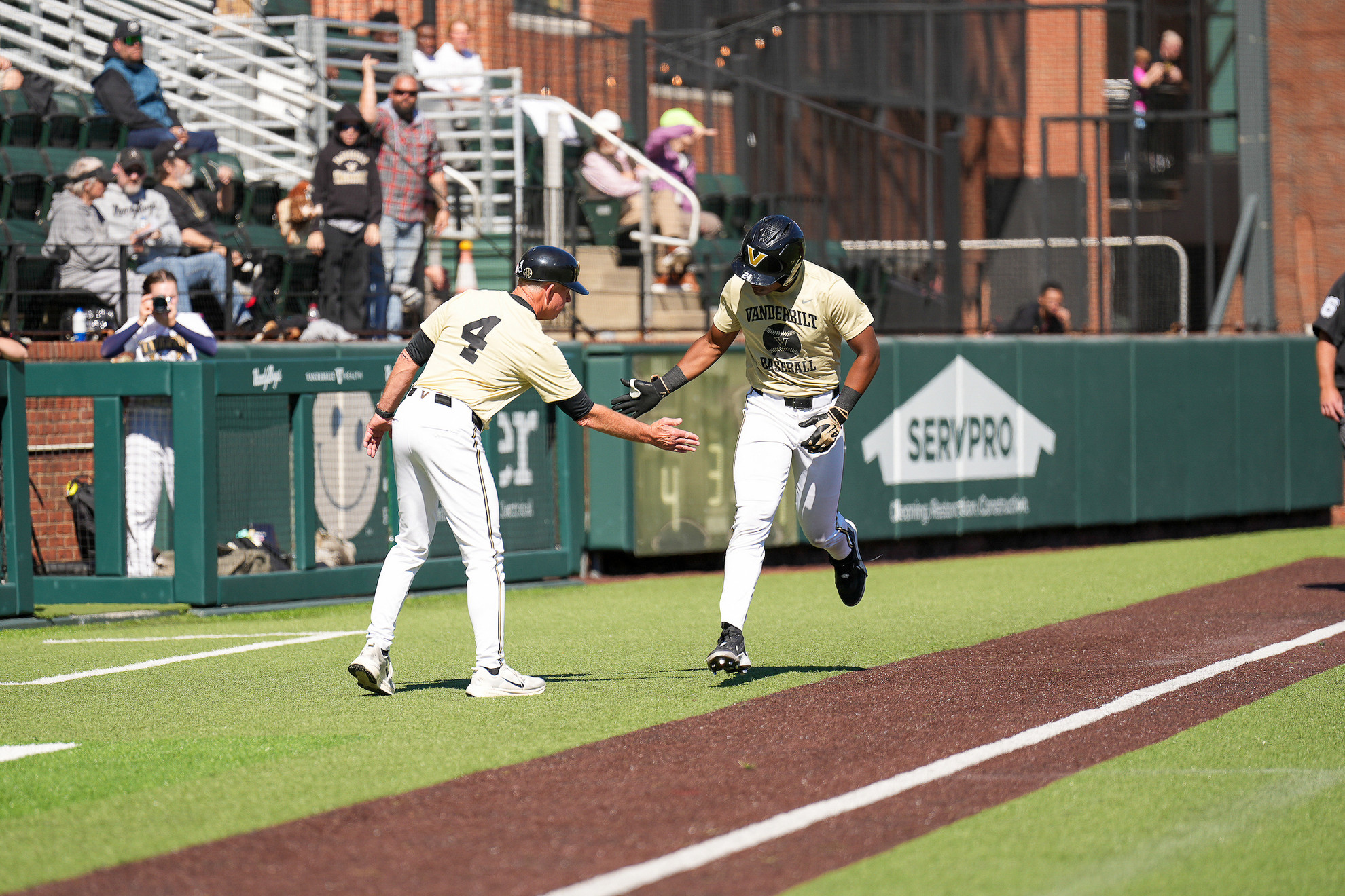 A Vanderbilt player rounds third base and high-fives a coach during the Commodores' fall exhibition at Hawkins Field.