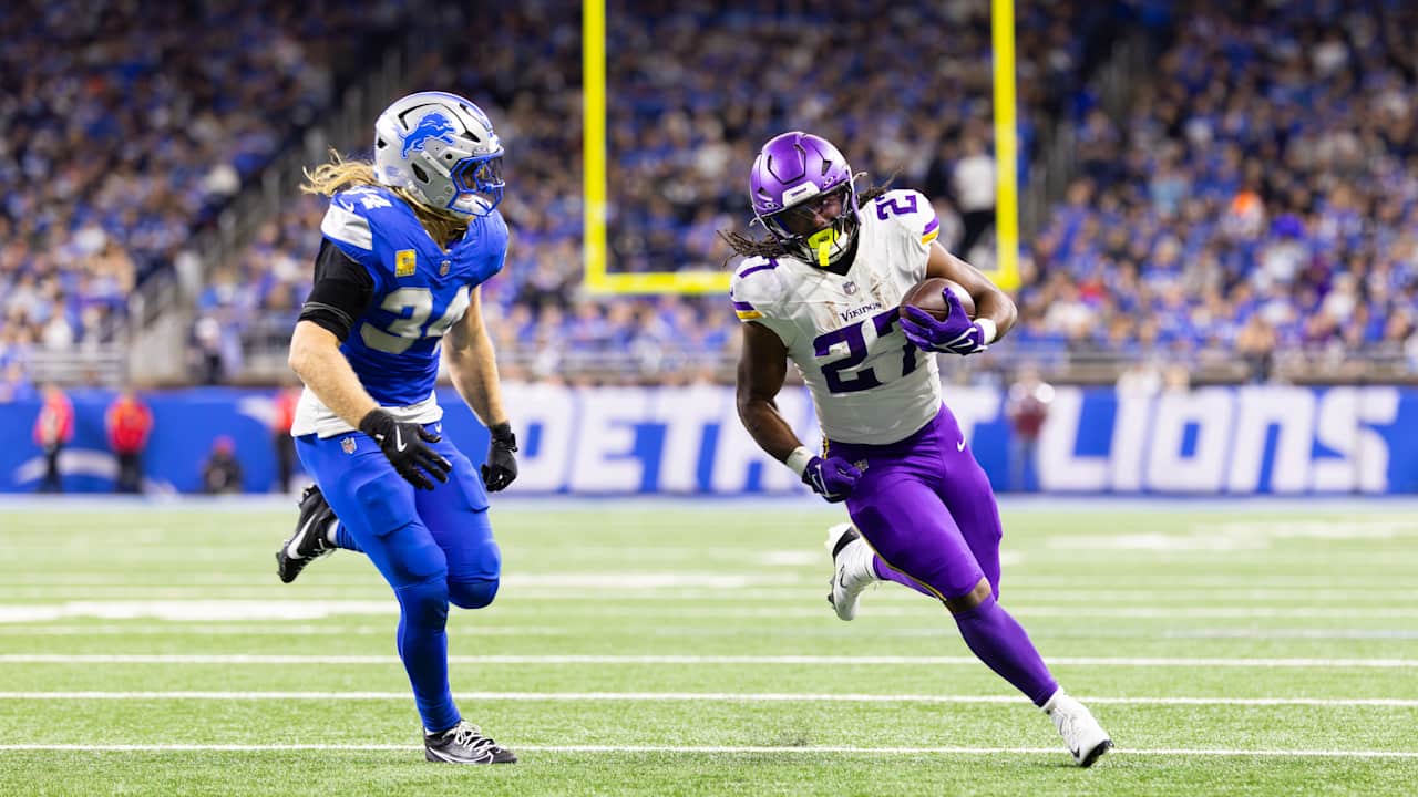 A Minnesota Vikings running back carries the ball past a Detroit Lions defender at Ford Field.